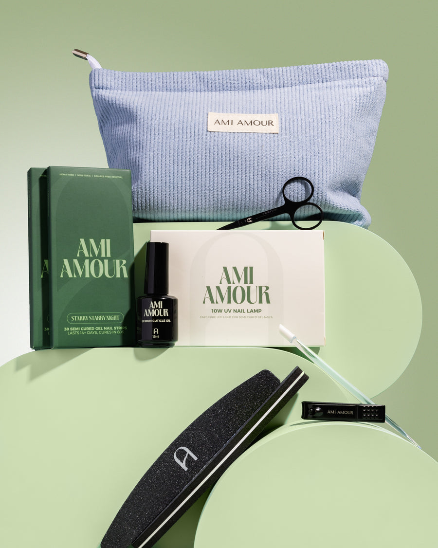 Mani starter kit contents — blue Ami Amour pouch with top coat, file, clippers and prep tools on sage green.